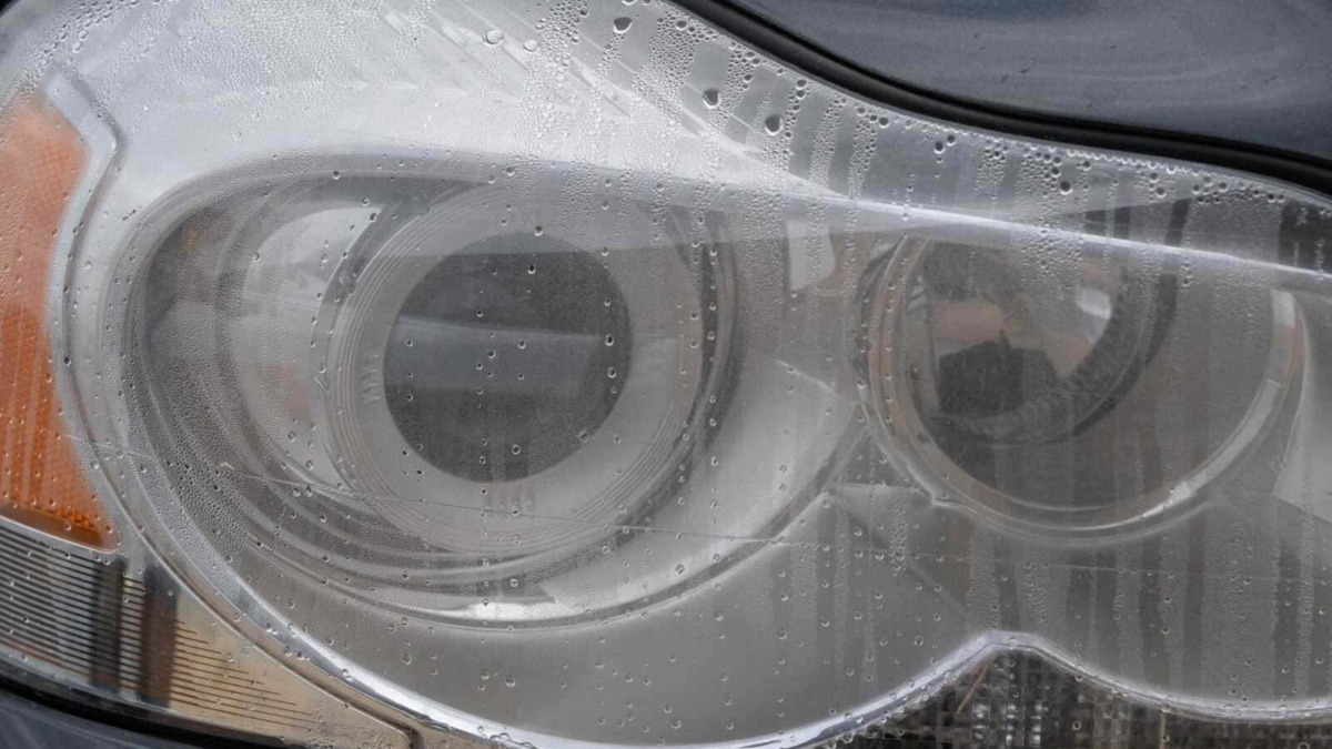 Pulizia fari auto con acqua e detergente, dettagliata immagine di lampada anteriore lucida e brillante. Rafforza la cura dell'auto, manutenzione e motori.