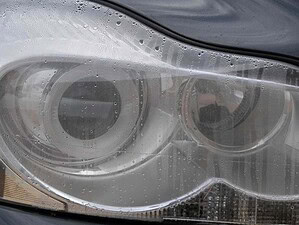 Pulizia fari auto con acqua e detergente, dettagliata immagine di lampada anteriore lucida e brillante. Rafforza la cura dell'auto, manutenzione e motori.