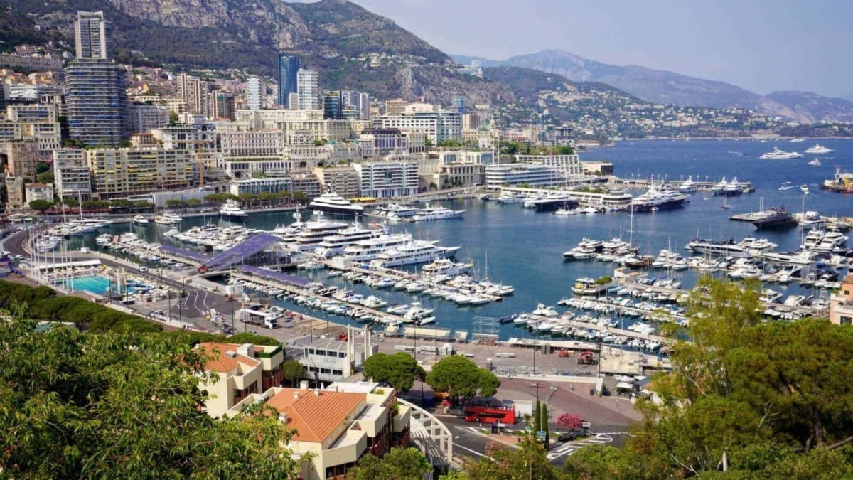 Vasche di diporto e yacht nel porto di Monaco con skyline urbano e montagne sullo sfondo, viste panoramiche ideali per blog di viaggi di lusso e itinerari sul blog Appunti Sul Blog.