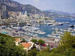 Vasche di diporto e yacht nel porto di Monaco con skyline urbano e montagne sullo sfondo, viste panoramiche ideali per blog di viaggi di lusso e itinerari sul blog Appunti Sul Blog.