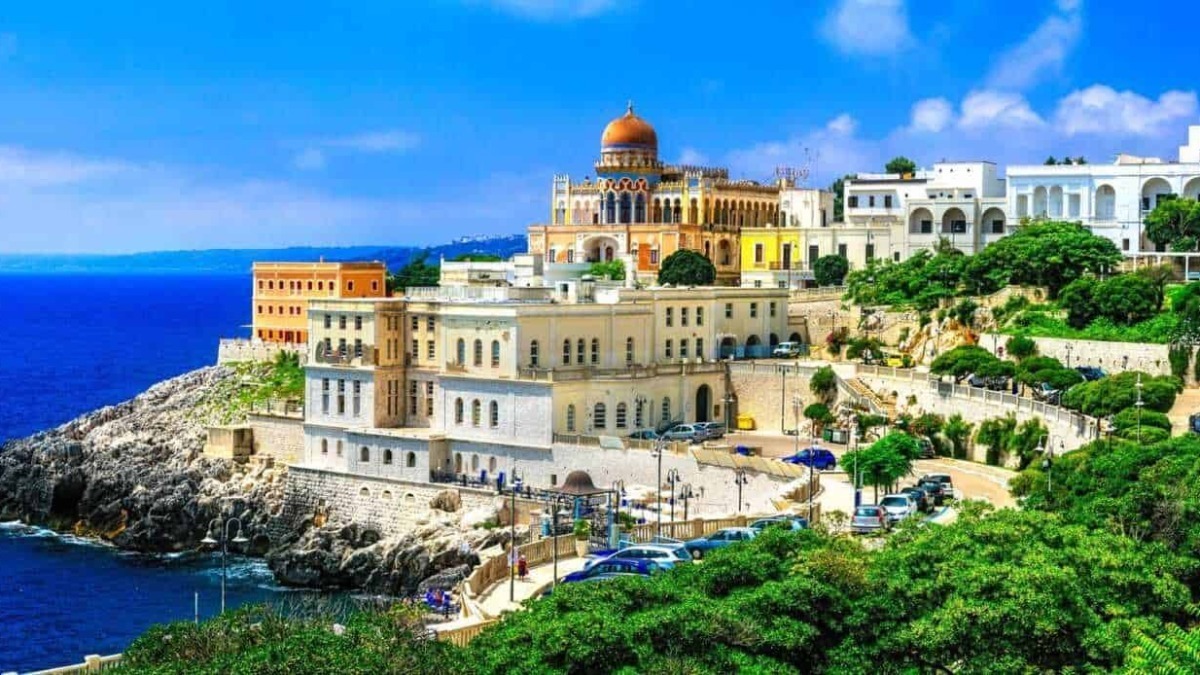 Palazzo storico sulla scogliera con vista sul mare in Costiera Amalfitana, Italia, paesaggio mediterraneo con case colorate e vegetazione rigogliosa.