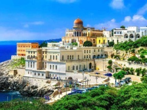 Palazzo storico sulla scogliera con vista sul mare in Costiera Amalfitana, Italia, paesaggio mediterraneo con case colorate e vegetazione rigogliosa.