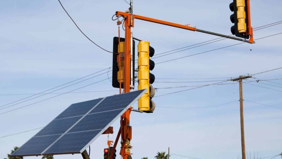 Pannello solare e semaforo intelligente sulla strada con sfondo cielo azzurro.