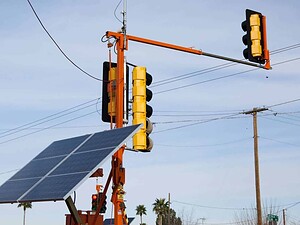Pannello solare e semaforo intelligente sulla strada con sfondo cielo azzurro.