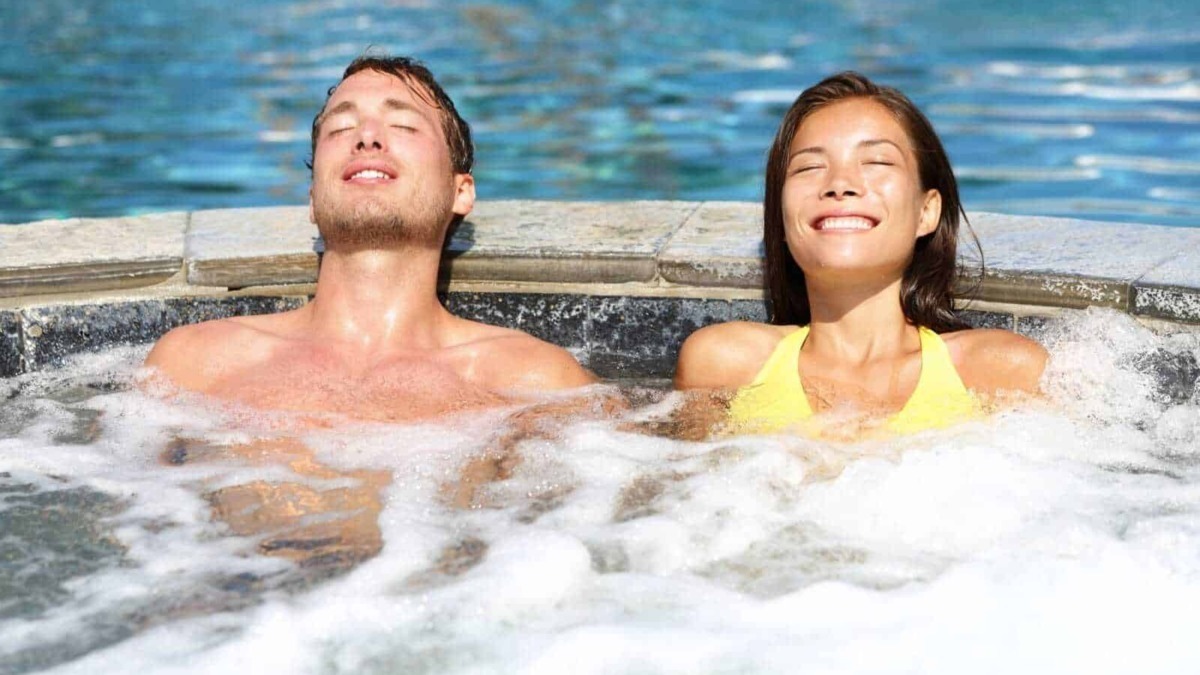Rilassamento in acqua calda in spa all'aperto, giovani coppie che si godono massaggi e benessere, benessere, relax e terapia termale.