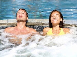 Rilassamento in acqua calda in spa all'aperto, giovani coppie che si godono massaggi e benessere, benessere, relax e terapia termale.