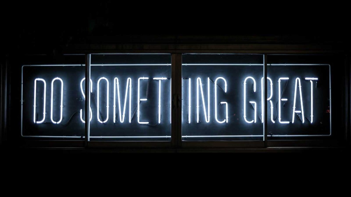 Scritte neon luminose "Do Something Great" su sfondo scuro, messaggio motivazionale in stile urban e motivazionale.