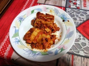 Figli di lasagna fatti in casa con besciamella e pomodoro, serviti in un piatto decorato, su tavolo con tovaglia colorata, deliziose e tradizionali ricette italiane.