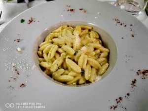 Crema di pasta fresca con formaggio e spezie, piatto tipico italiano servito in un ristorante elegante, perfetto per gli amanti della cucina tradizionale e gourmet.