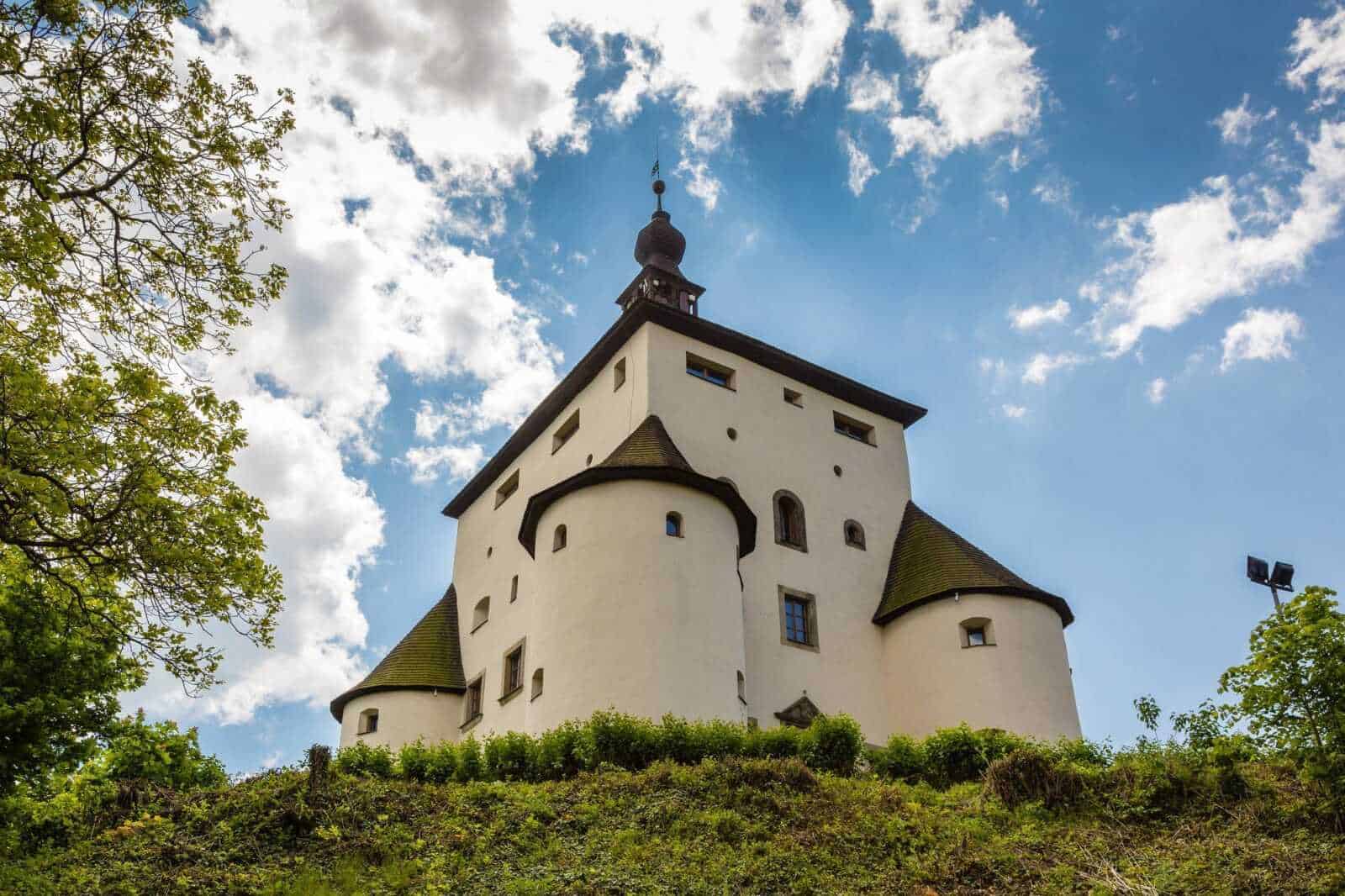 Romanzo horror Dracula: Dracula netflix: Castello medievale in collina con cielo azzurro e nuvole bianche, architettura storica, panorama delle Torri in Austria, attrazioni turistiche, struttura immersa nel verde, edificio storico, viaggio culturale, paesaggio pittoresco, monumento storico, escursioni in montagna, destinazioni Europee, patrimonio UNESCO, avventure e storia.
