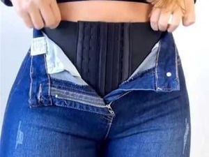 Cintura e jeans aperti, mostra una donna che si sta preparando a indossare un pantalone.