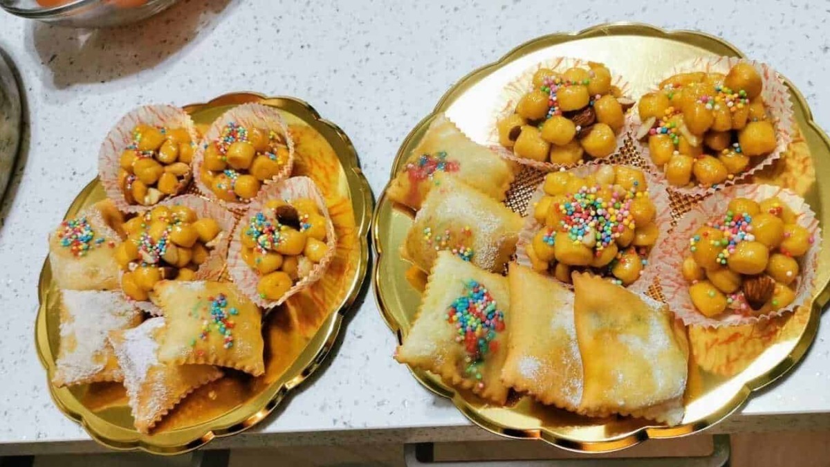 Frutti di Sant'Antonio, dolcetti tradizionali italiani con albicocche candite e palline di marzapane decorati con confetti colorati, disposti su vassoi dorati.