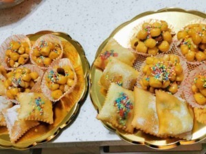 Frutti di Sant'Antonio, dolcetti tradizionali italiani con albicocche candite e palline di marzapane decorati con confetti colorati, disposti su vassoi dorati.