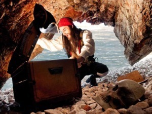 Teschio e scatola di legno in una grotta sulla spiaggia con uomo pirata in costume, avventura piratesca, scoperta segreti nascosti, atmosfera misteriosa e ambiente marino.