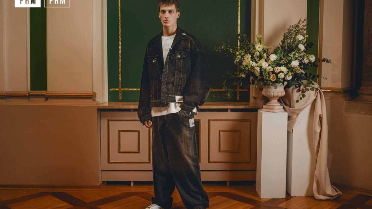 Vestito jeans maschile, stile streetwear, look casual, moda uomo, outfit denim nero, giovane uomo moda, pantaloni larghi, sneakers bianche, scena elegante, ambiente raffinato.