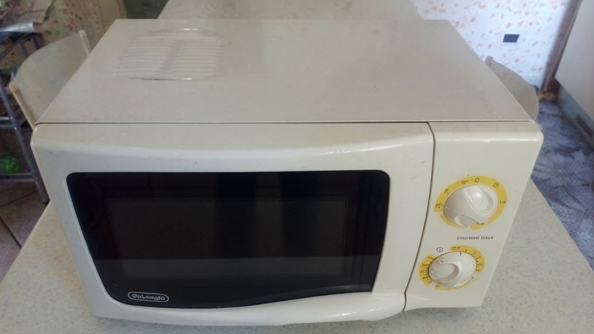 Microonde da cucina bianco con manopole gialle e display digitale, ideale per riscaldare e preparare alimenti in cucina.