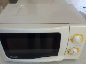 Microonde da cucina bianco con manopole gialle e display digitale, ideale per riscaldare e preparare alimenti in cucina.