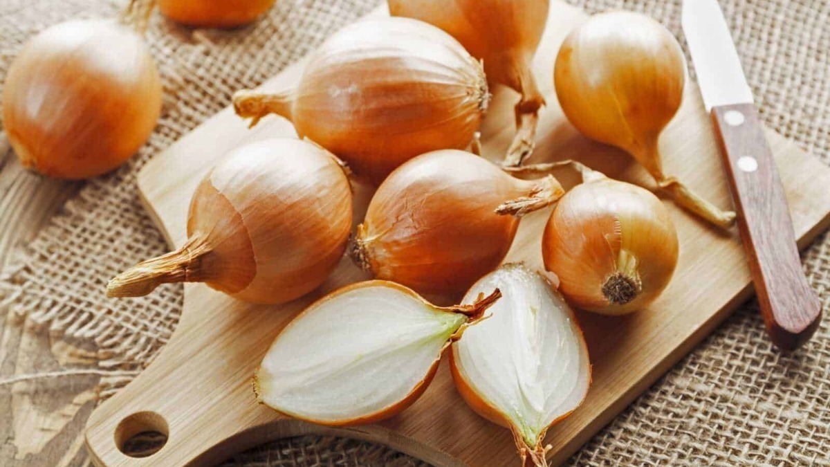 Aglio fresco e schiacciato su tagliere di legno con coltello, saporito ingrediente per cucina tradizionale italiana, ideale per condimenti e ricette casalinghe.