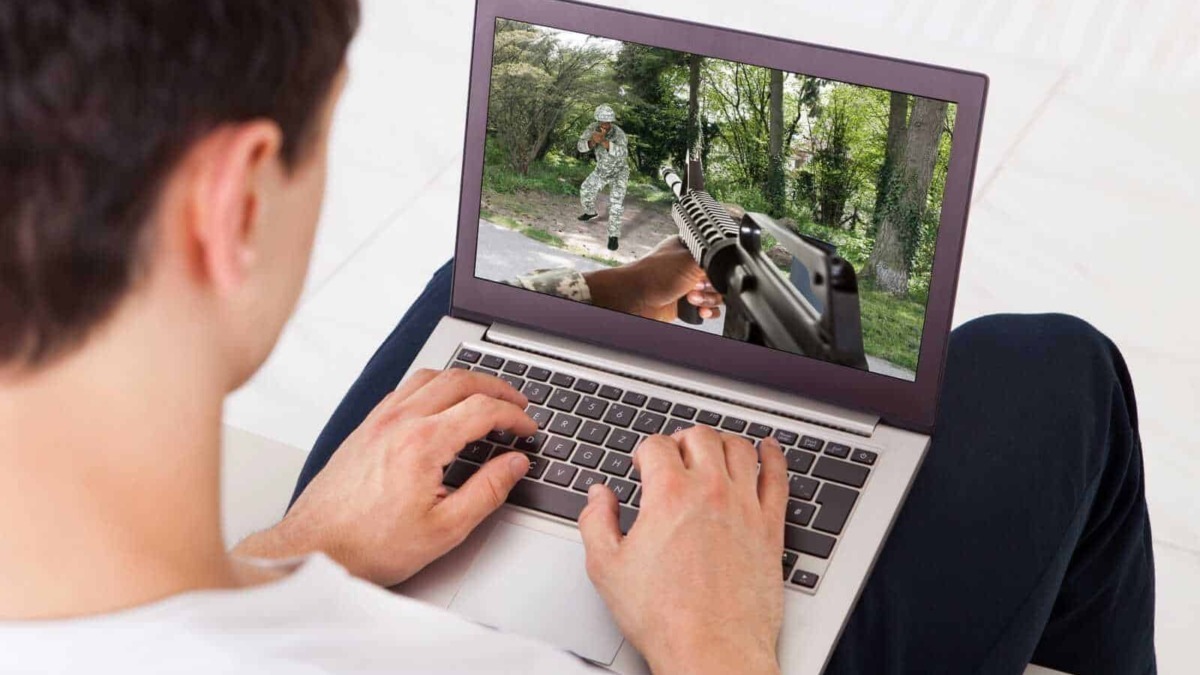 Tastiera di computer portatile con immagine di guerra in realtà virtuale, scena di esercitazione militare all'aperto, digitalizzazione di simulazioni di combattimento, tecnologia e videogiochi.