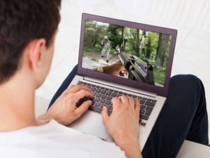 Tastiera di computer portatile con immagine di guerra in realtà virtuale, scena di esercitazione militare all'aperto, digitalizzazione di simulazioni di combattimento, tecnologia e videogiochi.