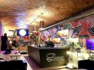 Atmosfera moderna e colorata in un bar con arredi trendy, pareti decorate con murales astratti, luci soffuse e un'ampia area lounge, ideale per serate social e eventi nel centro di Milano.