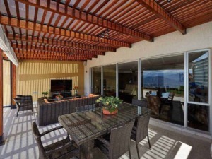 Copertura in legno e mobili da esterno su terrazza con vista sul mare, area soggiorno e zona pranzo all'aperto, ambiente accogliente e elegante per relax e convivialità all'aperto.