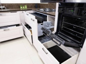 Ripiano cottura a gas e forno elettrico aperto in cucina moderna con mobili bianchi e dettagli neri, vista da vicino.