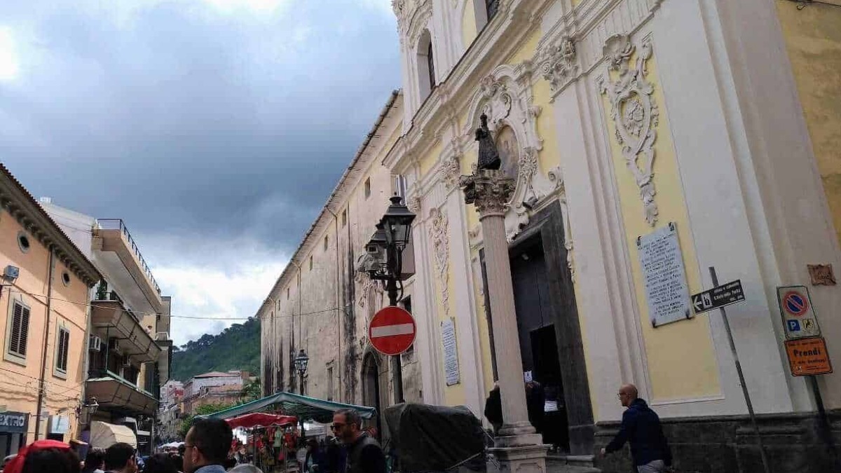 Storia e architettura barocca di una chiesa artistica nel centro storico di Napoli, con dettagli decorativi, statue e affreschi, circondata da un vivace mercato cittadino con turisti e cittadini.