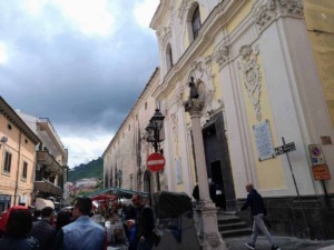 Storia e architettura barocca di una chiesa artistica nel centro storico di Napoli, con dettagli decorativi, statue e affreschi, circondata da un vivace mercato cittadino con turisti e cittadini.