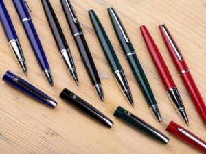 Penna stilografica di diversi colori, perfetta per scrittura elegante e professionale, su superficie in legno naturale.