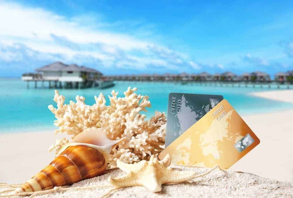 Carte di credito sulla spiaggia con conchiglie e corallo, paradiso tropicale, vacanze al mare, overwater bungalows, resort di lusso, estate, relax, destinazioni esclusive, viaggio.
