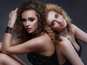 Vedi donne con capelli ricci e trucco glamour in uno scatto artistico, perfetto per blog di moda e lifestyle.