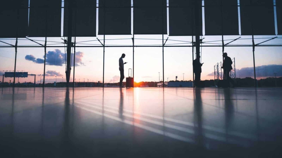 Aereoporto con silhouette di persone al tramonto, sottolineando viaggi, aeroporti e mobilità in Italia.