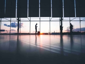 Aereoporto con silhouette di persone al tramonto, sottolineando viaggi, aeroporti e mobilità in Italia.
