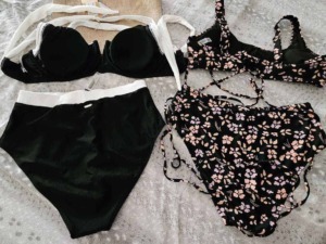 Lingerie elegantemente disposta su un letto con lenzuola chiare, includendo un reggiseno nero con pizzo.