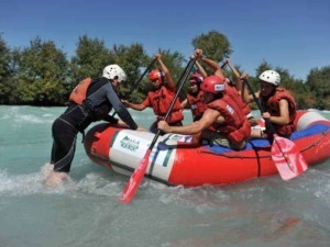 Escursionisti in raft sul fiume con guide esperte, attività di rafting avventurosa e sicura in natura. Riva di fiume e vegetazione sullo sfondo, esperienza outdoor per amanti dell'avventura.