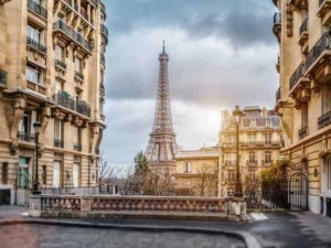 Eiffel Tower vista da un quartiere di Parigi, Francia, con edifici in stile classico francese e una strada tranquilla sotto un cielo nuvoloso, al tramonto.