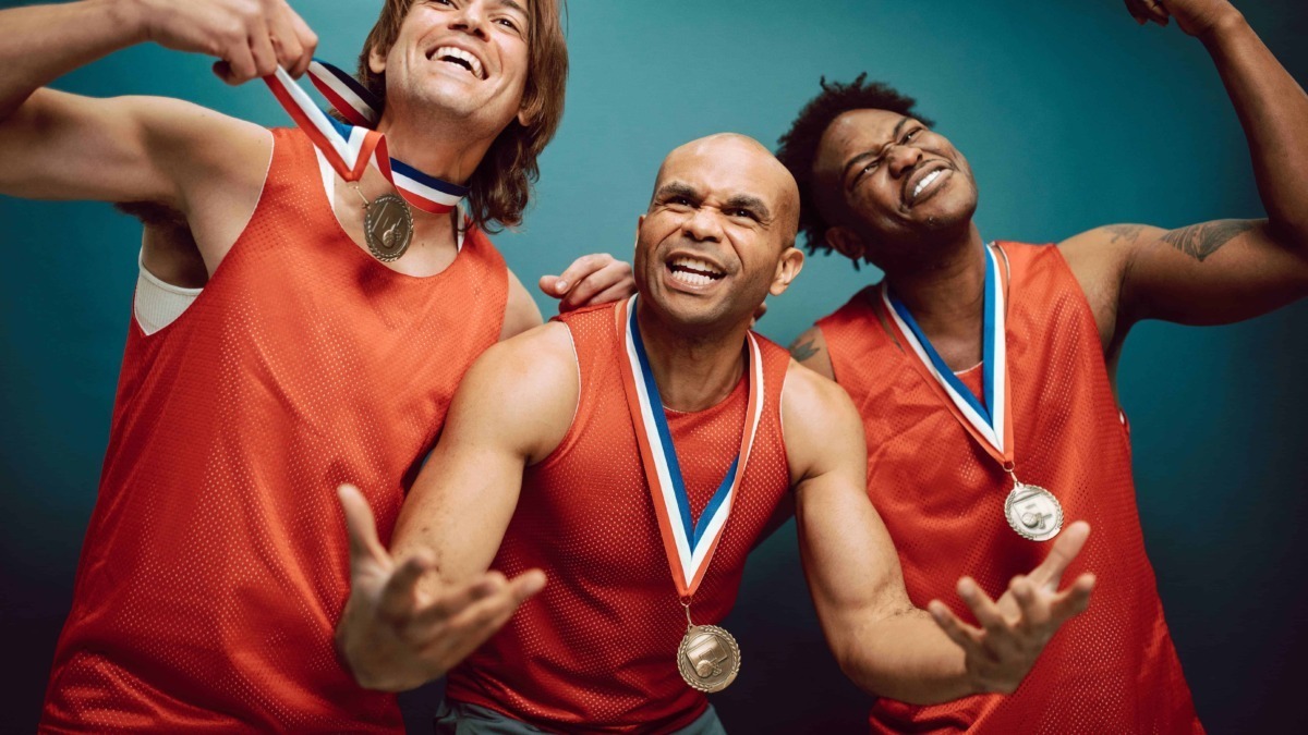Vincitori alle Olimpiadi con medaglie d'oro, sorridenti e festeggianti dopo la vittoria, indossano divise sportive rosse e mostrano orgoglio e felicità.