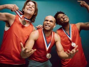 Vincitori alle Olimpiadi con medaglie d'oro, sorridenti e festeggianti dopo la vittoria, indossano divise sportive rosse e mostrano orgoglio e felicità.