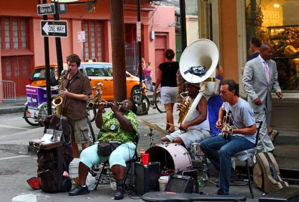 Accordi musicali di street band jazz con musicisti che suonano strumenti come sax, tromba, tuba e chitarra in un contesto urbano vivace e dinamico.