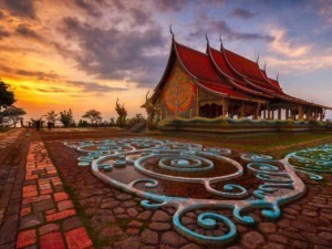Architettura tradizionale thailandese, tempio con tetto a più piani e decorazioni elaborati al tramonto, simbolo spiritualità e cultura asiatica, in un paesaggio suggestivo.