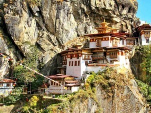 L'illustrativo monasteroBhutan, costruito su una scogliera di montagna, con tradizionale architettura tibetana, circondato da natura e decorazioni di preghiera.