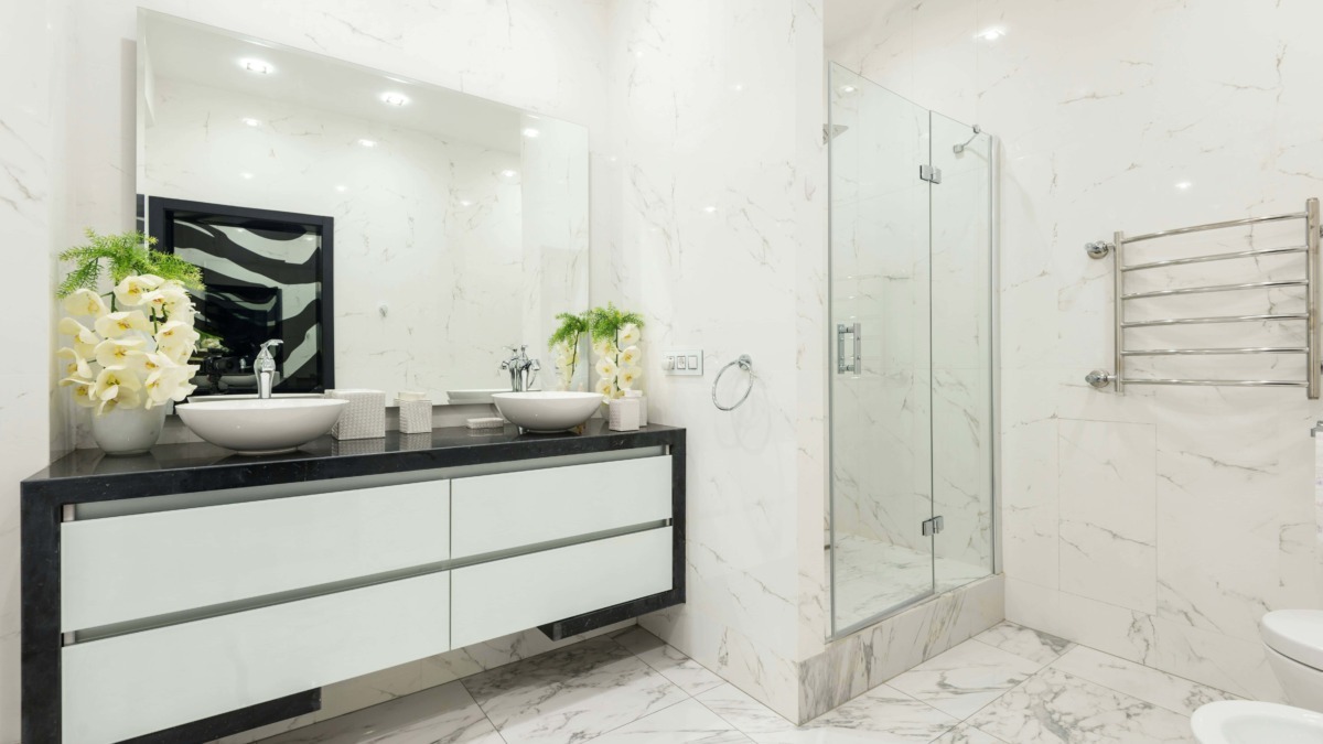 Lavabo doppio con piani in marmo nero e decorazioni floreali, bagno moderno con pareti in marmo bianco, doccia in vetro e riscaldamento asciugamani in acciaio, design elegante e di lusso.