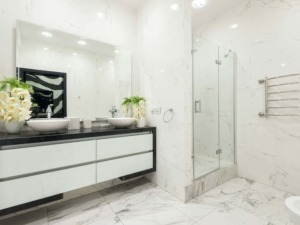 Lavabo doppio con piani in marmo nero e decorazioni floreali, bagno moderno con pareti in marmo bianco, doccia in vetro e riscaldamento asciugamani in acciaio, design elegante e di lusso.