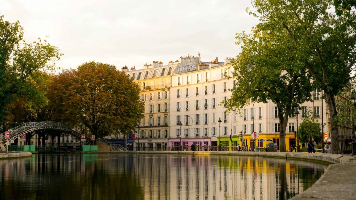 Ville di Parigi con edifici storici e alberi autunnali lungo il fiume con riflessi sull'acqua.