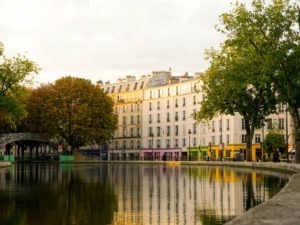 Ville di Parigi con edifici storici e alberi autunnali lungo il fiume con riflessi sull'acqua.