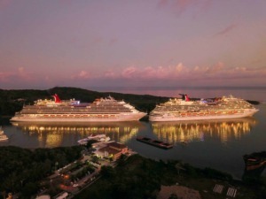 Gemelli di navi da crociera illuminati di sera in un porto marina, riflessi sull'acqua, paesaggio marittimo, vacanze, turismo, crociere di lusso, vista aerea, atmosfera rilassante, scena notturna.