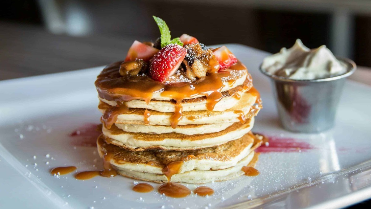 Deliziose pancake con frutta fresca, sciroppo d'acero e panna montata. Un dolce brunch perfetto per una colazione golosa e irresistibile.