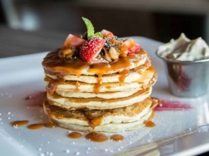 Deliziose pancake con frutta fresca, sciroppo d'acero e panna montata. Un dolce brunch perfetto per una colazione golosa e irresistibile.