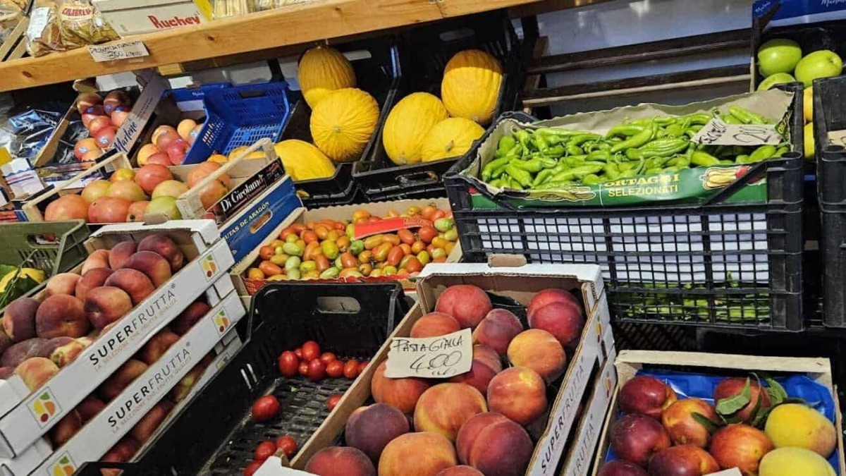 Pesche, meloni e verdure fresche in bancarella di mercato ortofrutta. Frutta di stagione e prodotti agricoli biologici disponibili per acquisto immediato.